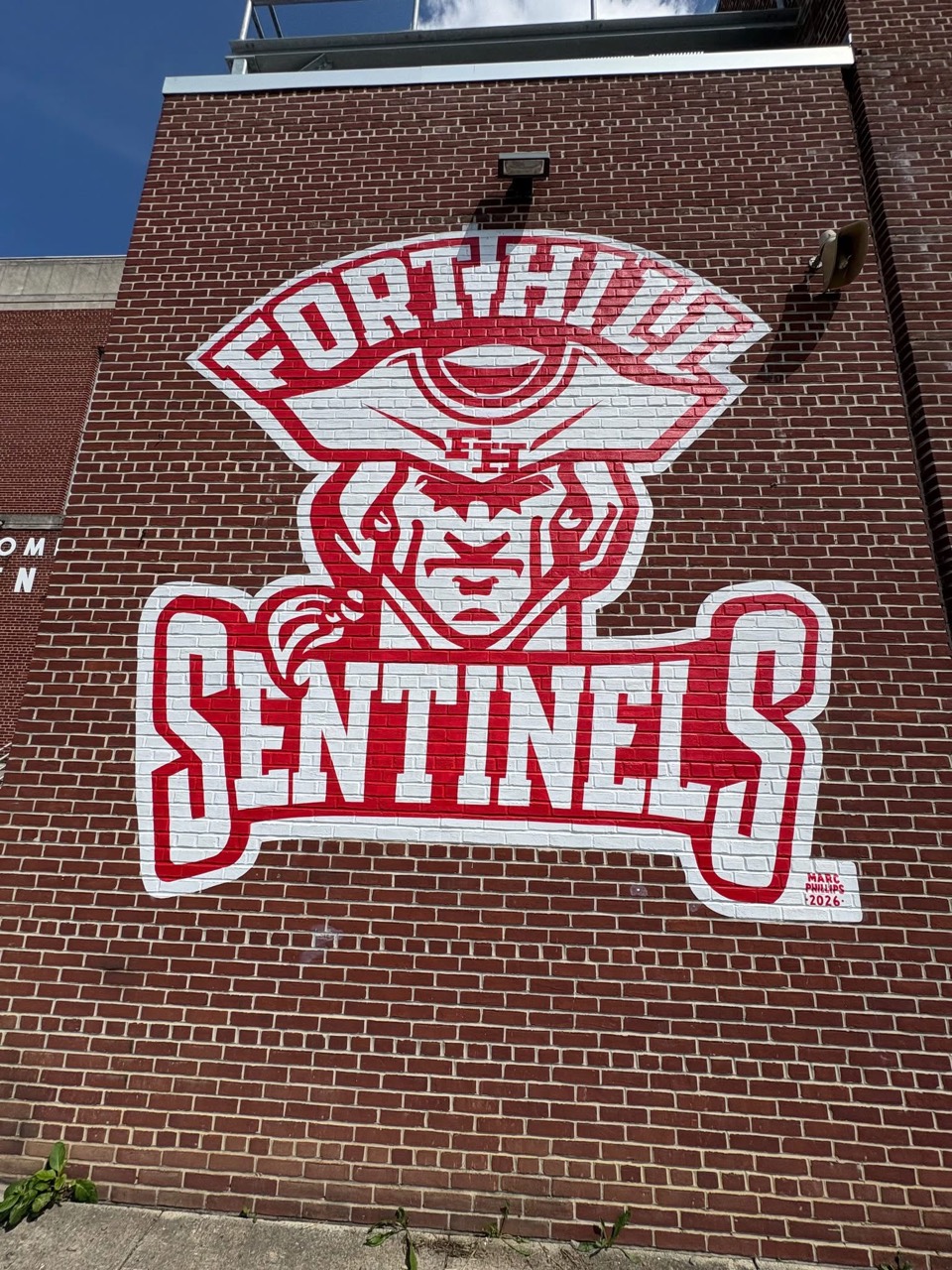 Red and white Fort Hill Sentinels mascot and lettering painted by Marc Phillips on an exterior brick wall at Fort Hill High School in Cumberland, Maryland